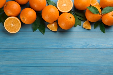 Photo of Delicious ripe oranges on light blue wooden table, flat lay. Space for text