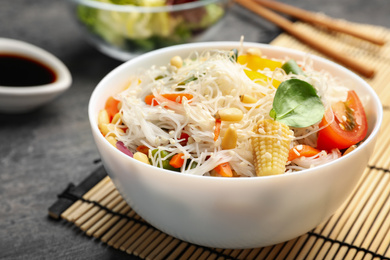 Photo of Tasty cooked rice noodles with vegetables on grey table