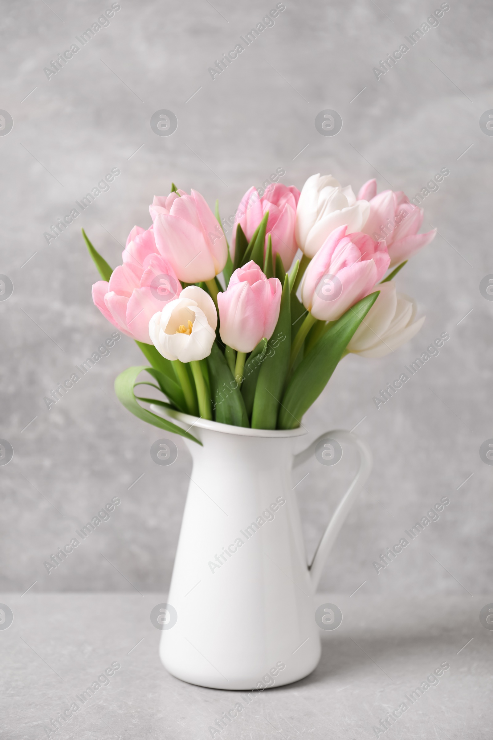 Photo of Beautiful bouquet of tulips in jug on light table