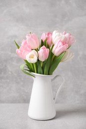 Beautiful bouquet of tulips in jug on light table