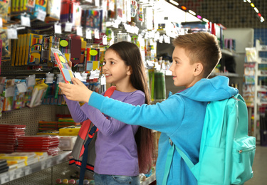 Little children choosing school stationery in supermarket