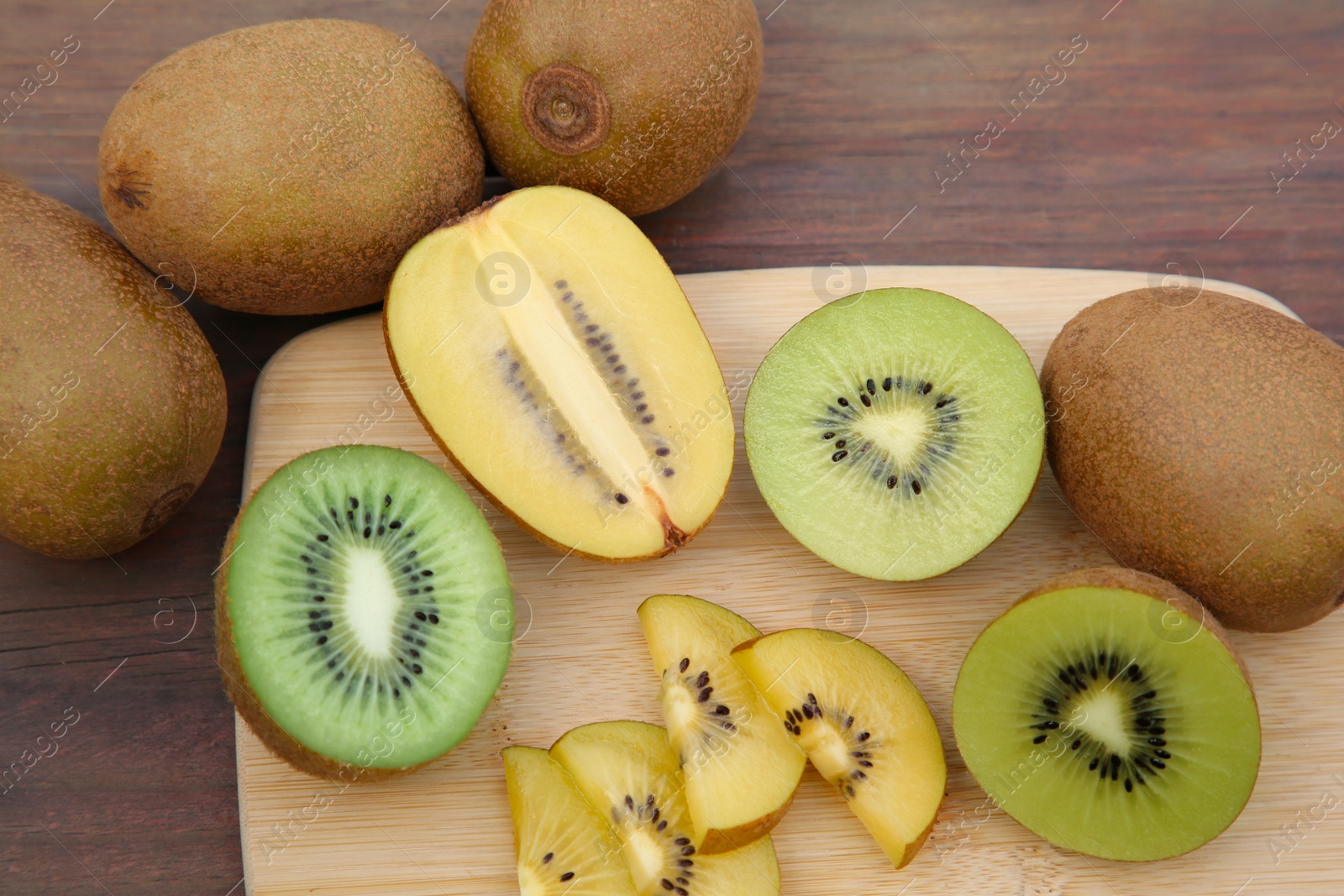 Photo of Whole and cut fresh kiwis on wooden table, above view