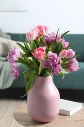 Photo of Beautiful bouquet of colorful tulip flowers on coffee table in room