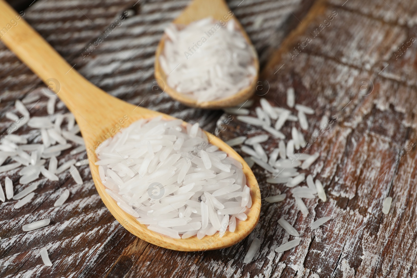 Photo of Raw basmati rice in spoon on wooden table, closeup