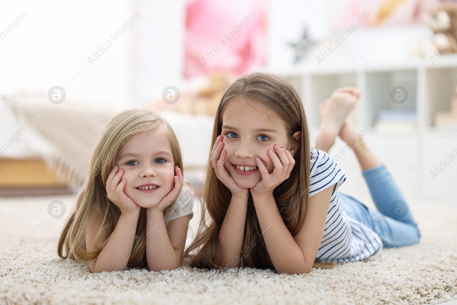 Photo of Cute little sisters on floor at home