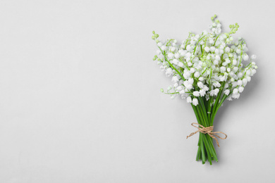 Beautiful lily of the valley flowers on light grey background, top view. Space for text