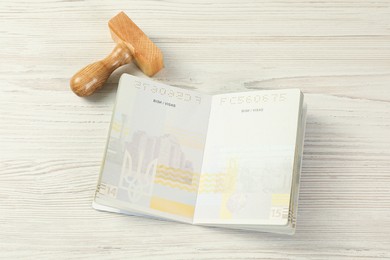 Photo of Moldova, Ceadir-Lunga - June 13, 2022: Wooden stamp and open passport with blank visa pages on white table