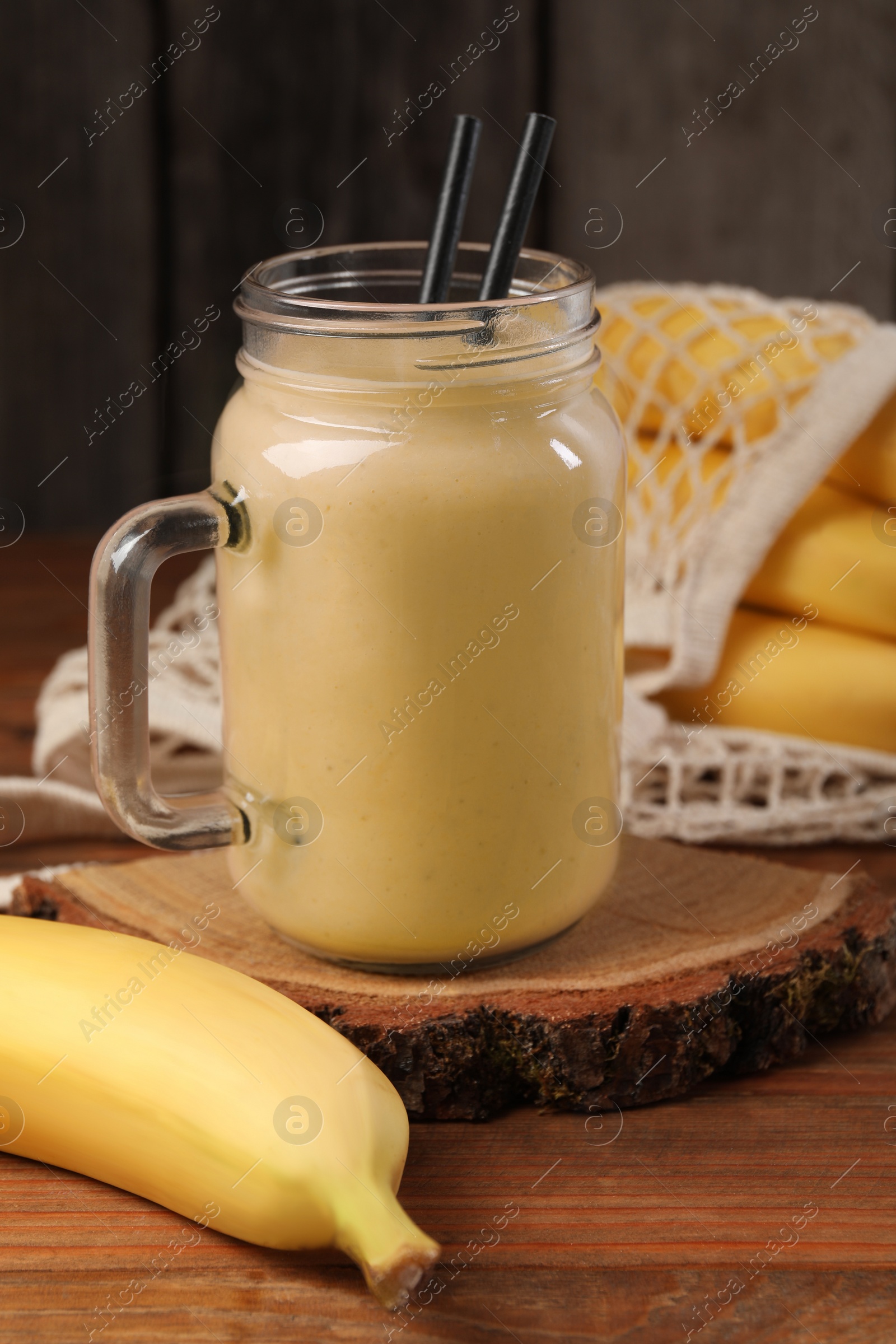 Photo of Mason jar with banana smoothie on wooden table