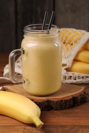 Photo of Mason jar with banana smoothie on wooden table