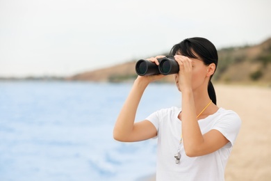 Photo of Beautiful female lifeguard with binocular near sea