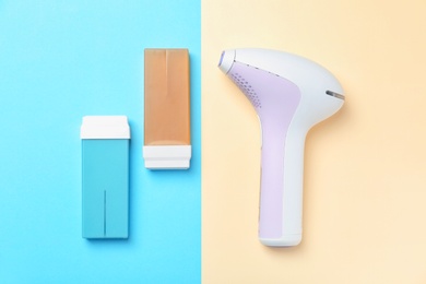 Photo of Modern laser epilator and wax cartridges on color background