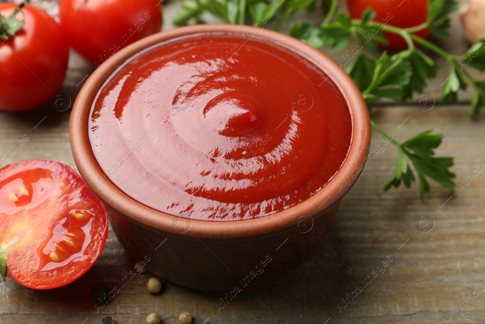 Photo of Tasty ketchup, fresh tomatoes, parsley and spices on wooden table, closeup