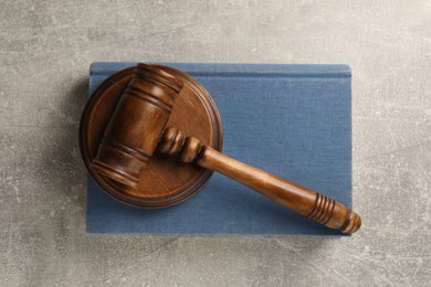 Photo of Wooden gavel, sound block and book on grey textured table, top view