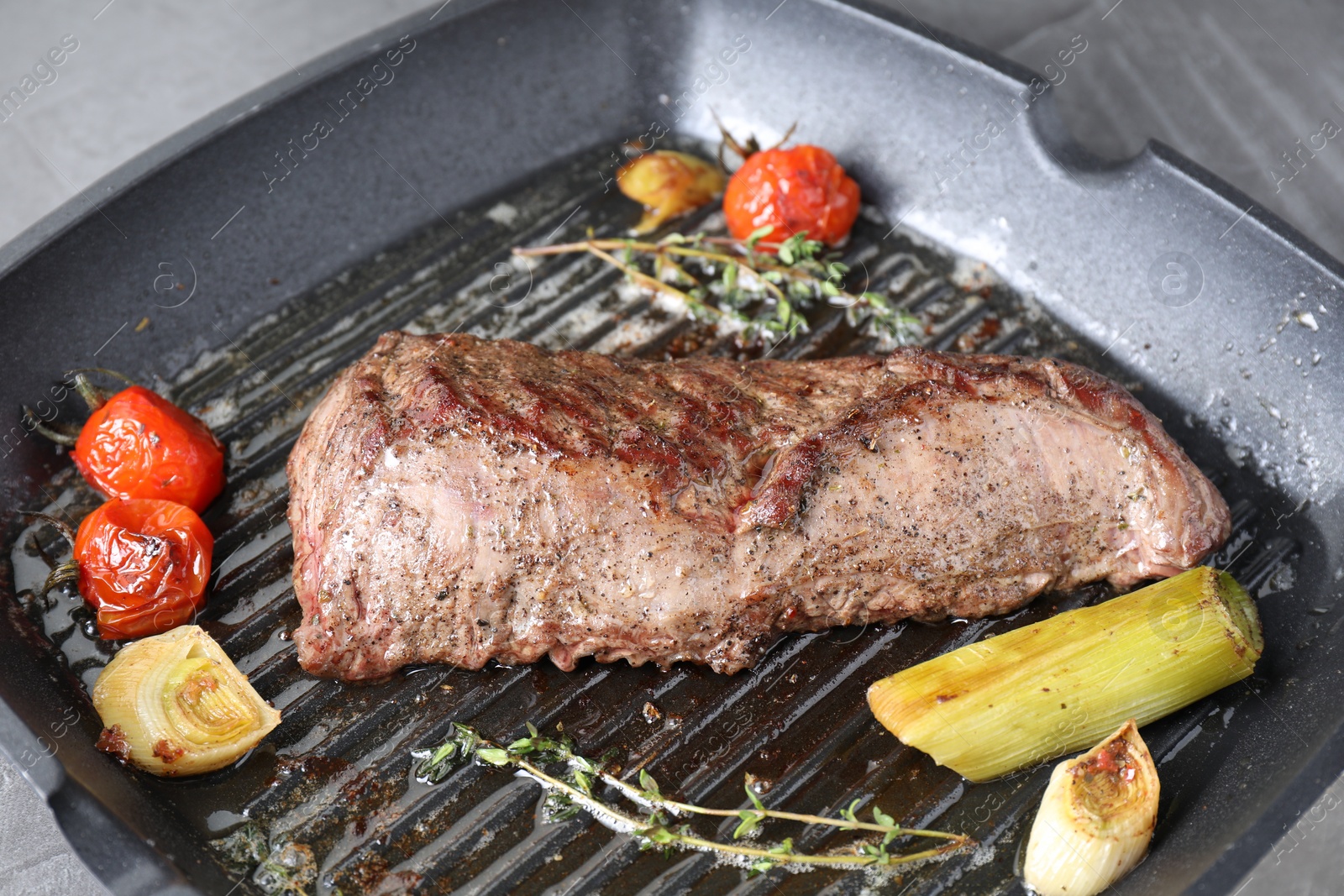 Photo of Delicious grilled beef meat and vegetables in pan on table, closeup