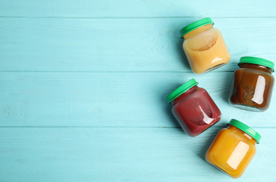 Jars with baby food on light blue wooden table, flat lay. Space for text