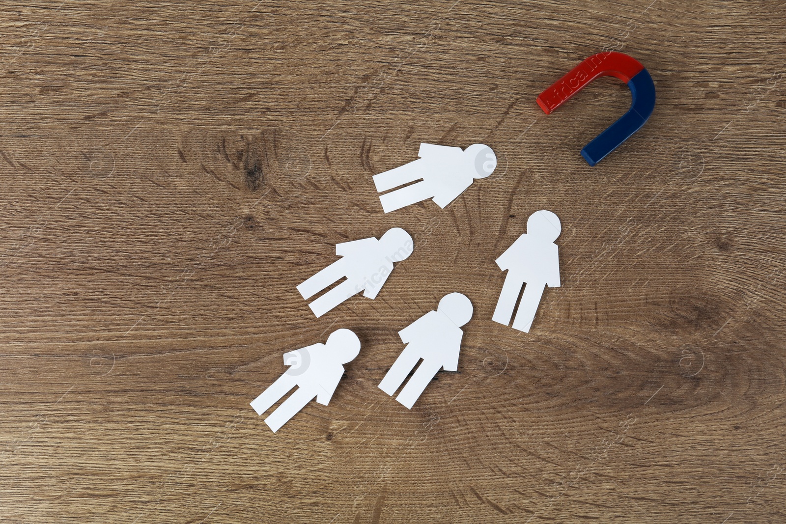 Photo of Magnet and paper people on wooden table, flat lay