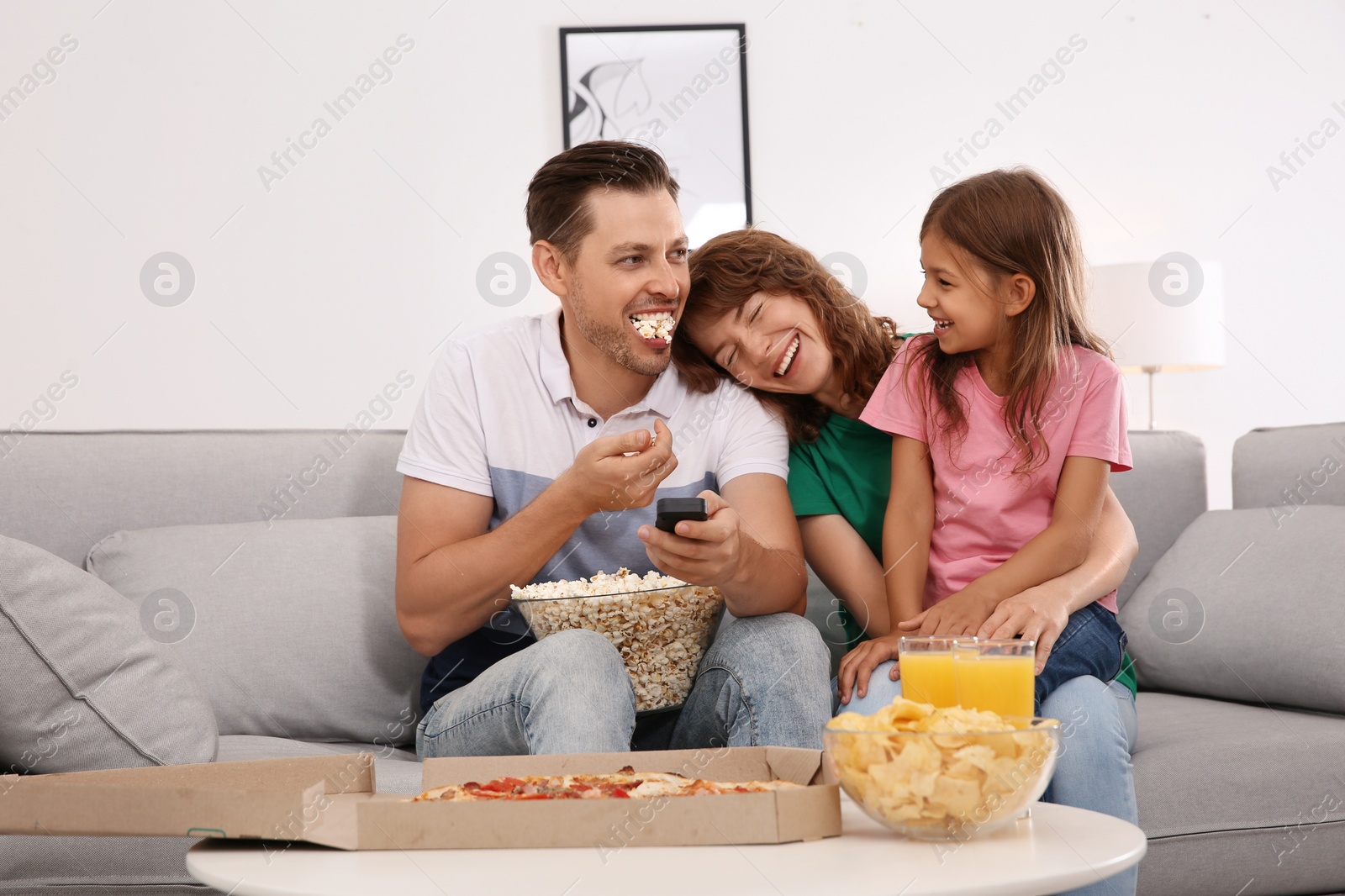 Photo of Family watching TV with popcorn in room