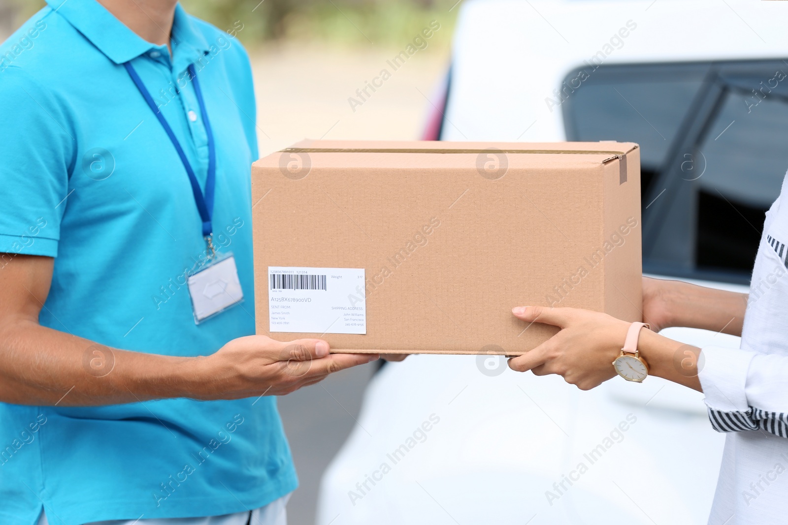 Photo of Young woman receiving parcel from courier outdoors