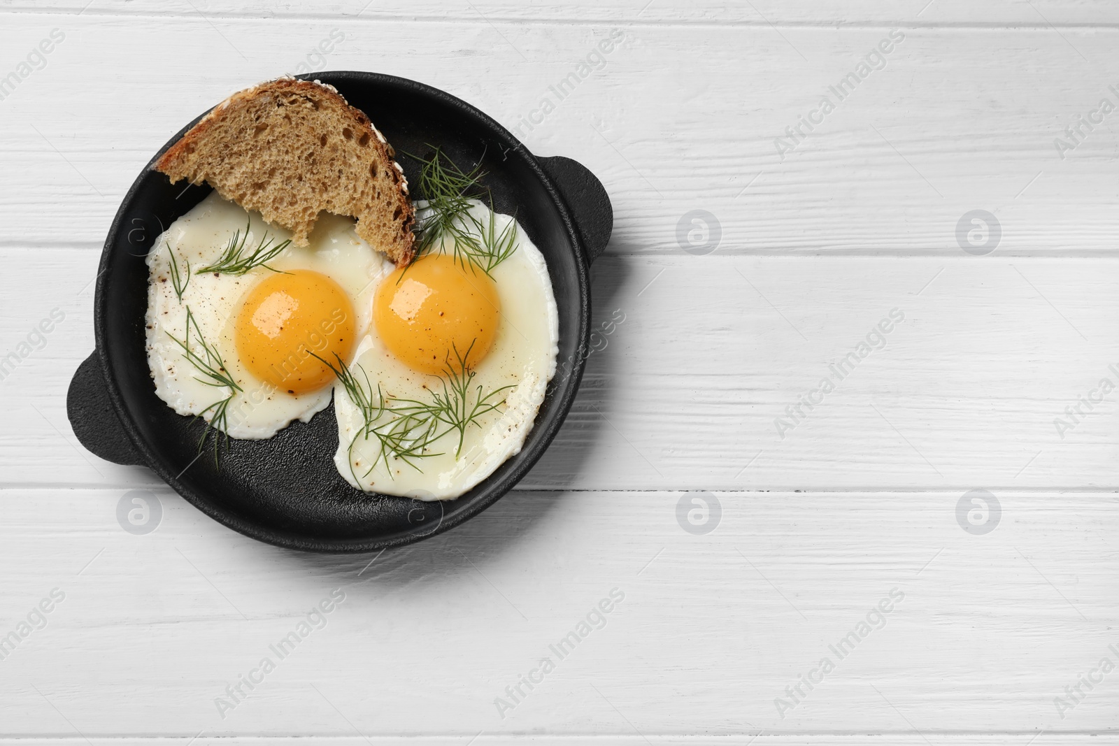 Photo of Delicious fried eggs served with bread on white wooden table, top view. Space for text