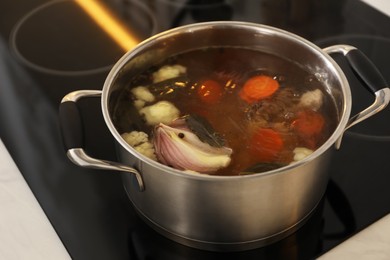 Photo of Pot with delicious bouillon on stove, closeup. Homemade recipe