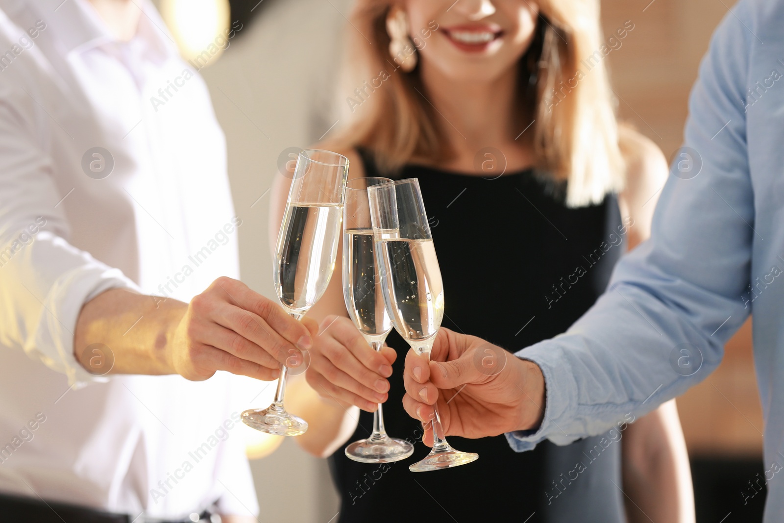 Photo of Friends clinking glasses with champagne at party indoors, closeup