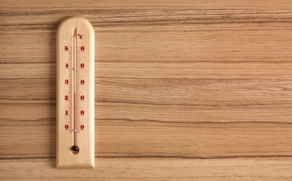 Weather thermometer on wooden table, top view. Space for text