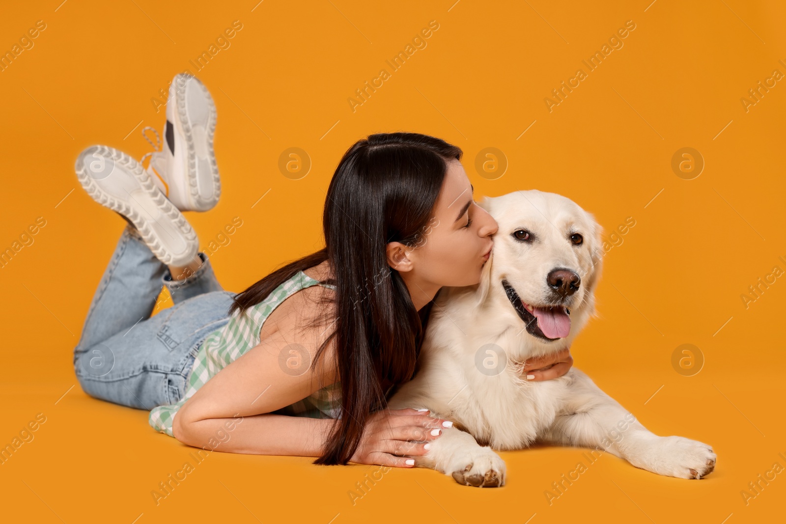 Photo of Woman with cute Labrador Retriever dog on orange background. Adorable pet