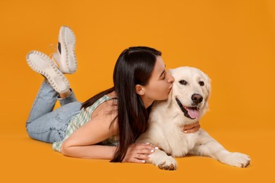 Woman with cute Labrador Retriever dog on orange background. Adorable pet
