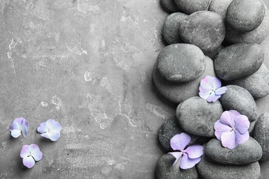 Photo of Zen stones and exotic flowers on grey background, top view with space for text