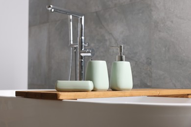 Photo of Set of bath accessories on tub in bathroom