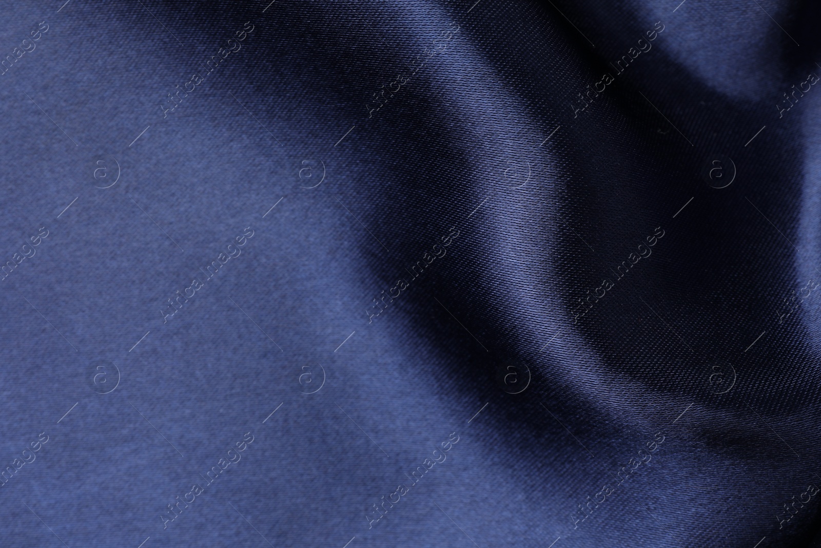 Photo of Crumpled dark blue silk fabric as background, closeup