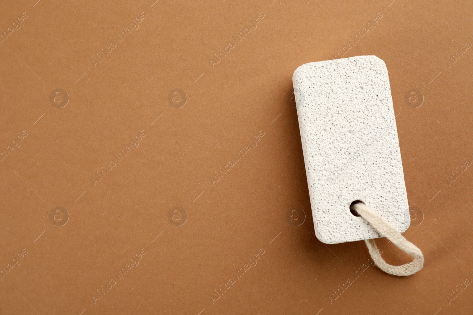 Photo of Pumice stone on brown background, top view. Space for text