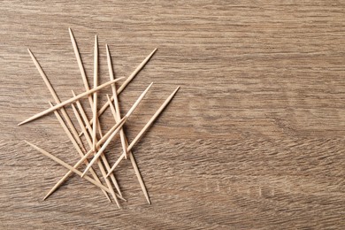 Photo of Disposable toothpicks on wooden background, flat lay. Space for text