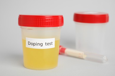 Photo of Jar with urine sample on light grey background, space for text. Doping control