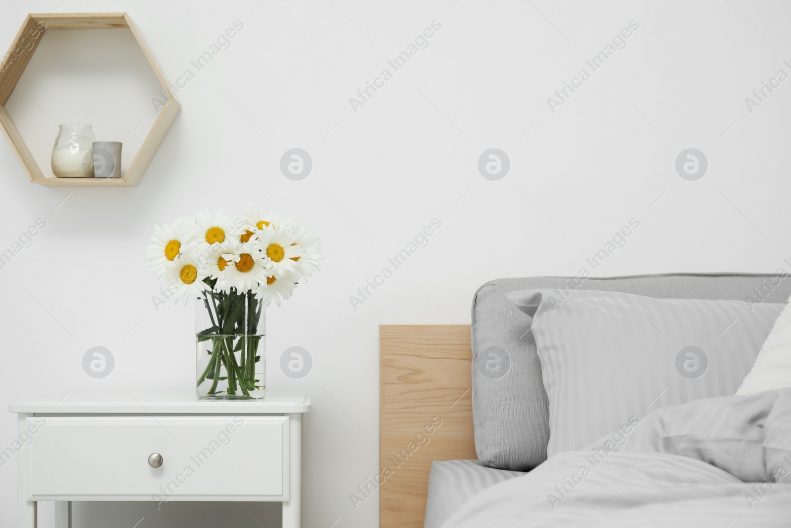 Photo of Bouquet of beautiful daisy flowers on nightstand in bedroom