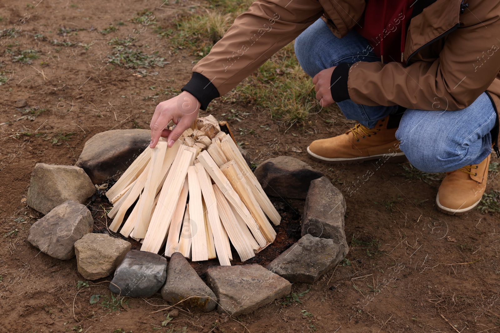 Photo of Man making bonfire outdoors, closeup. Camping season