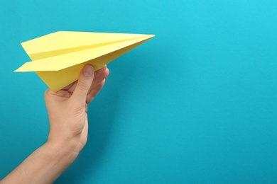 Photo of Woman holding paper plane on light blue background, closeup. Space for text