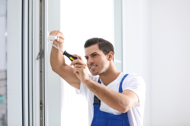 Construction worker repairing plastic window with screwdriver indoors