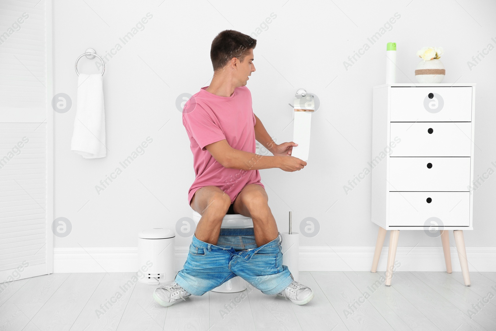 Photo of Young man sitting on toilet bowl at home