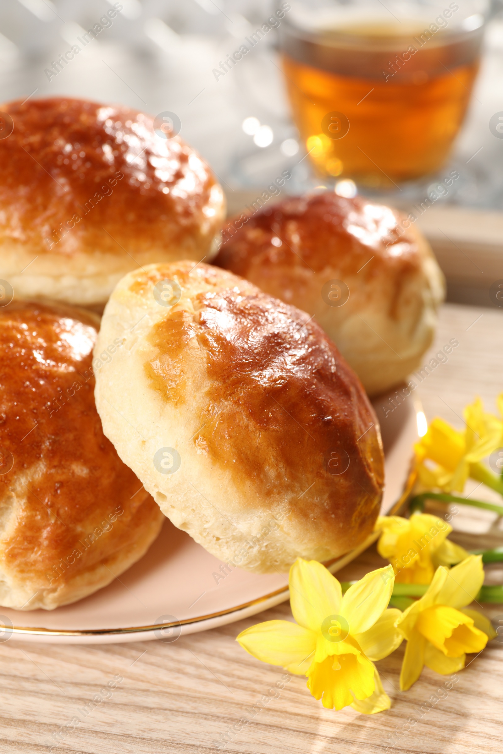 Photo of Freshly baked soda water scones and daffodils on wooden table, closeup