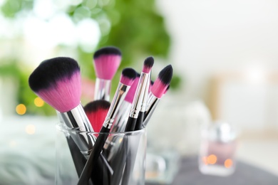 Makeup brushes in holder on blurred background