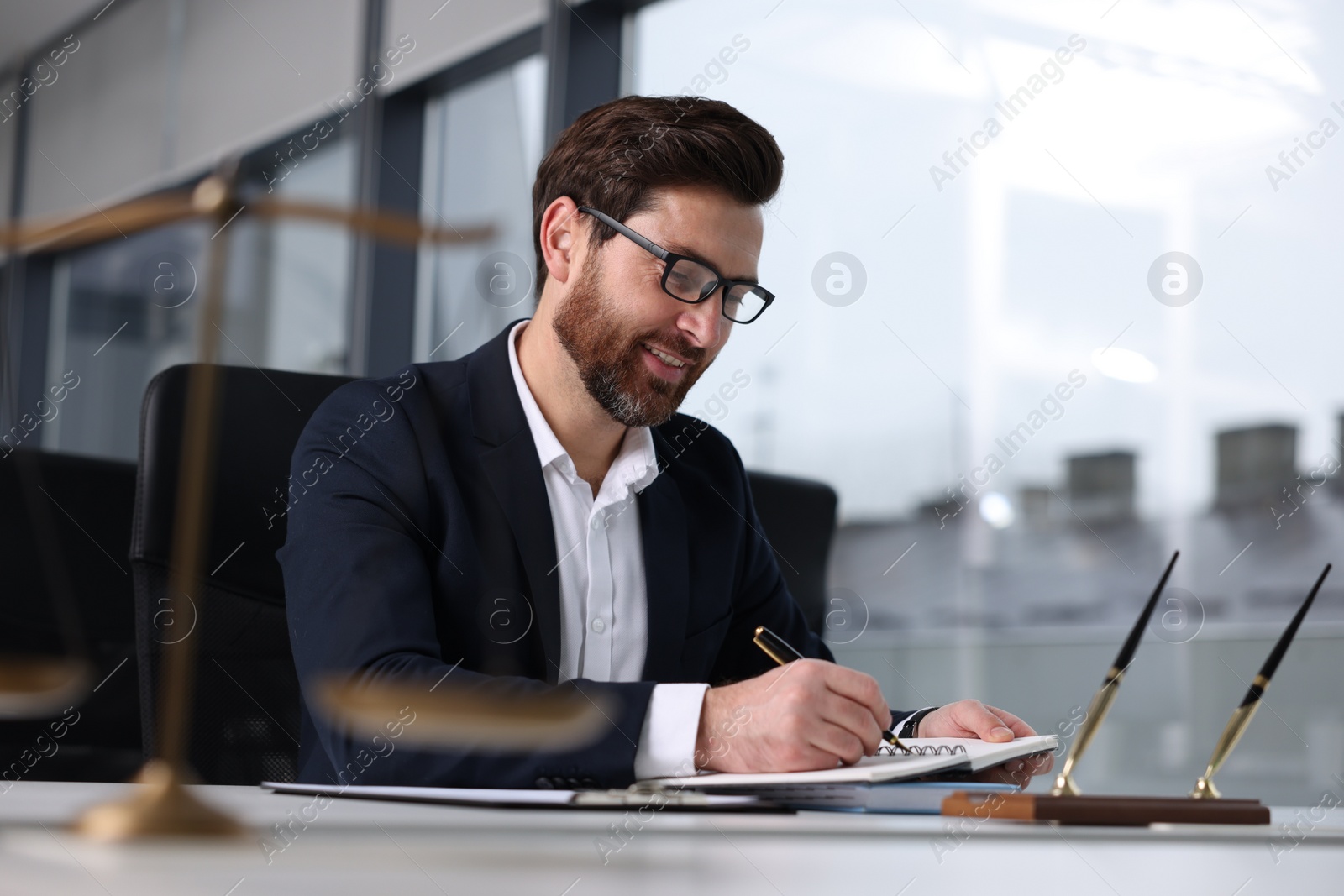 Photo of Smiling lawyer working at table in office