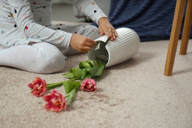Child and broken ceramic vase on floor at home, closeup