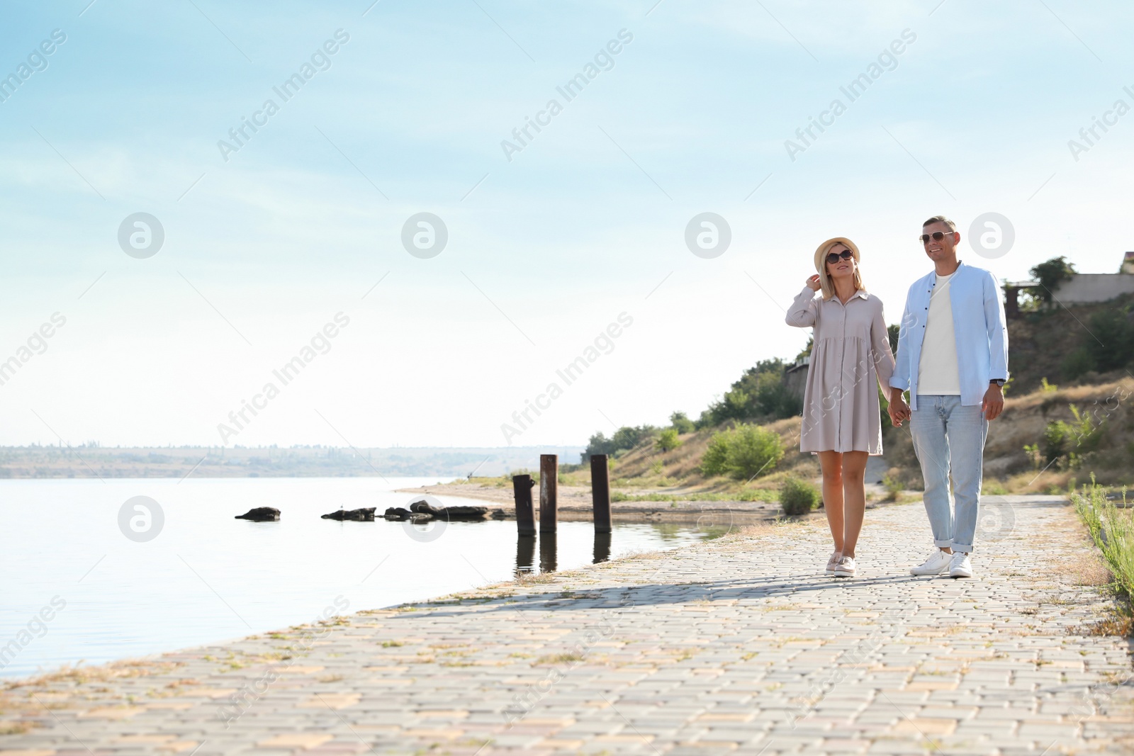 Photo of Happy couple walking along waterfront on summer day