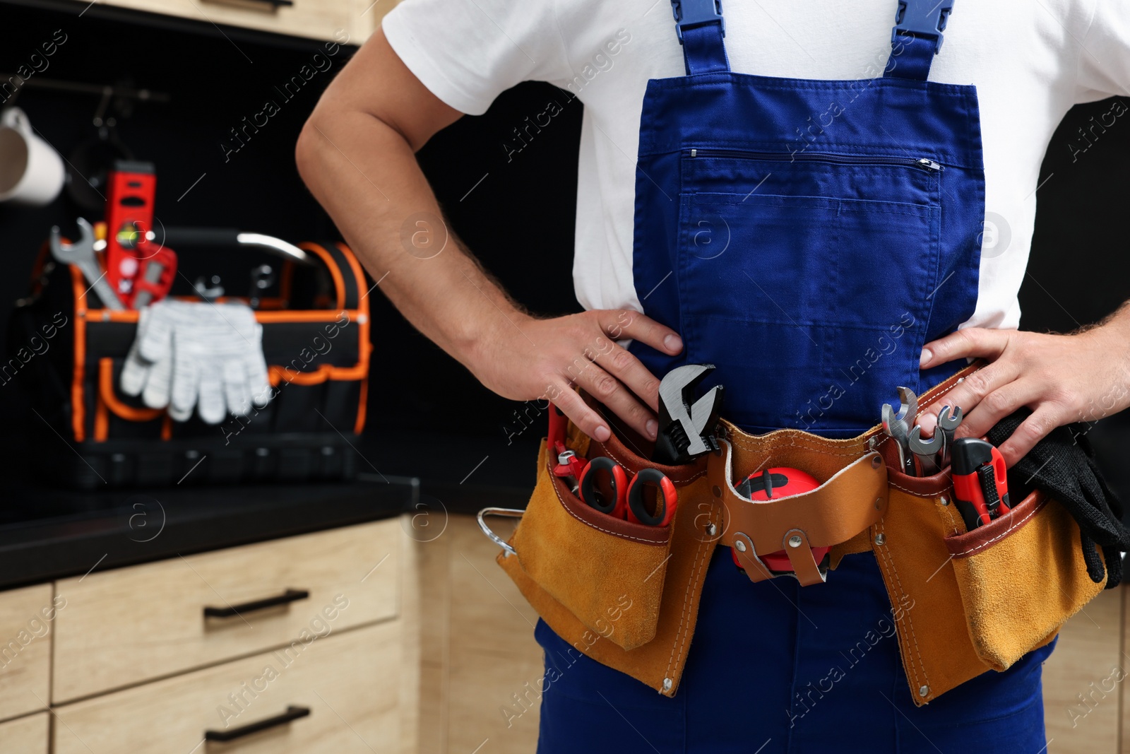 Photo of Professional plumber with tool belt indoors, closeup