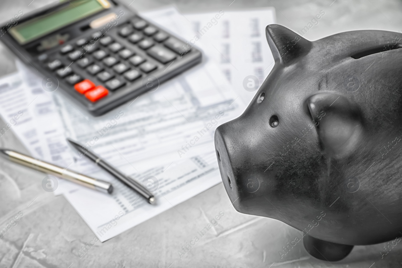 Photo of Black piggy bank, documents and calculator on table