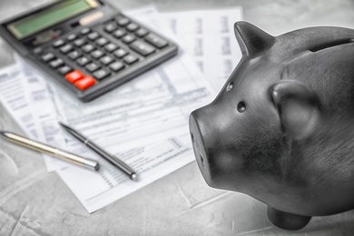Photo of Black piggy bank, documents and calculator on table