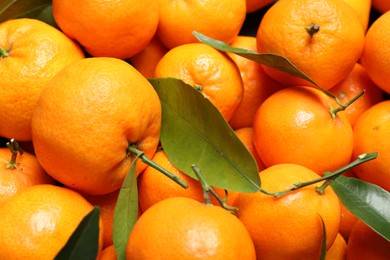 Photo of Fresh ripe tangerines with leaves as background, top view. Citrus fruit