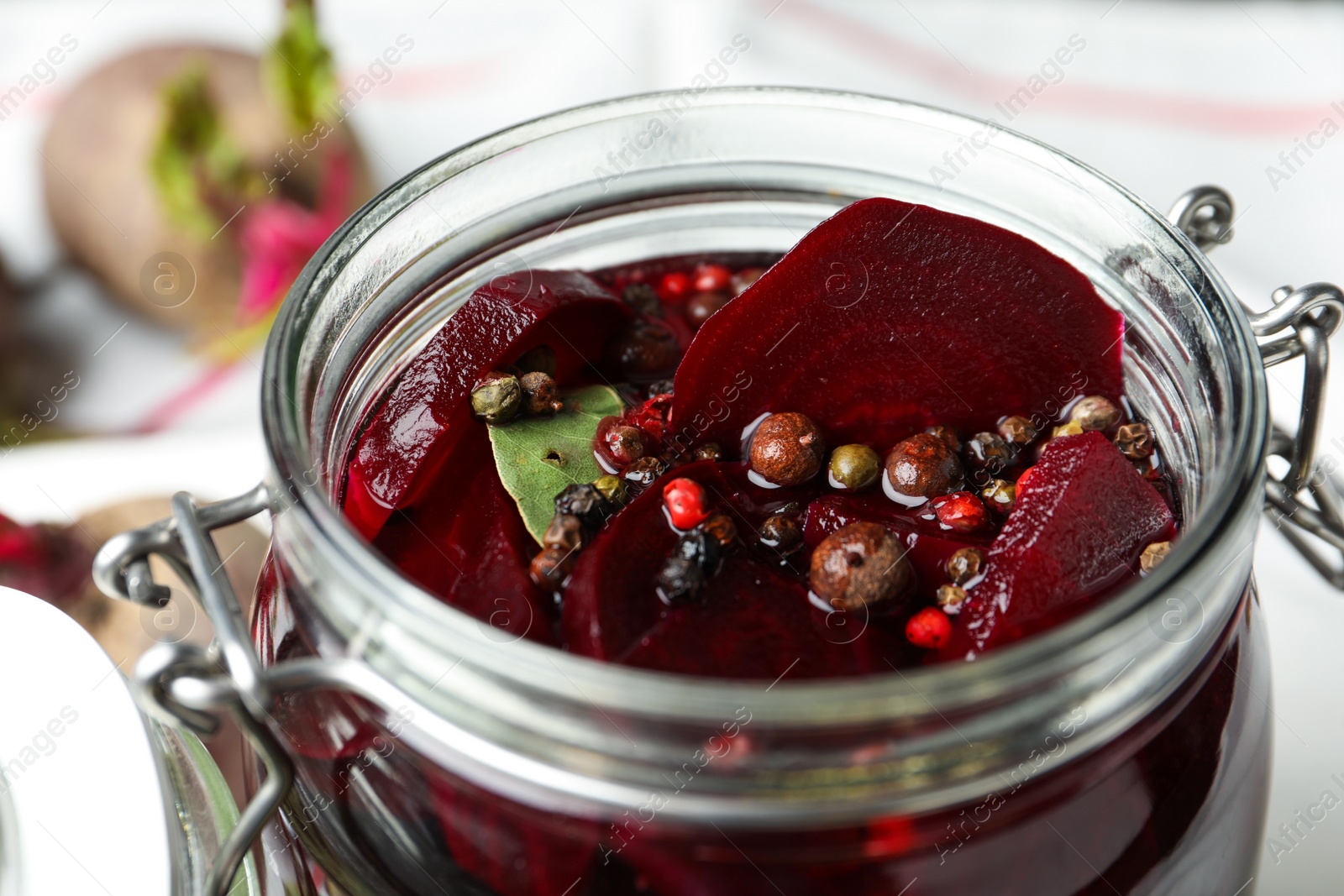 Photo of Pickled beets in glass preserving jar on table, closeup