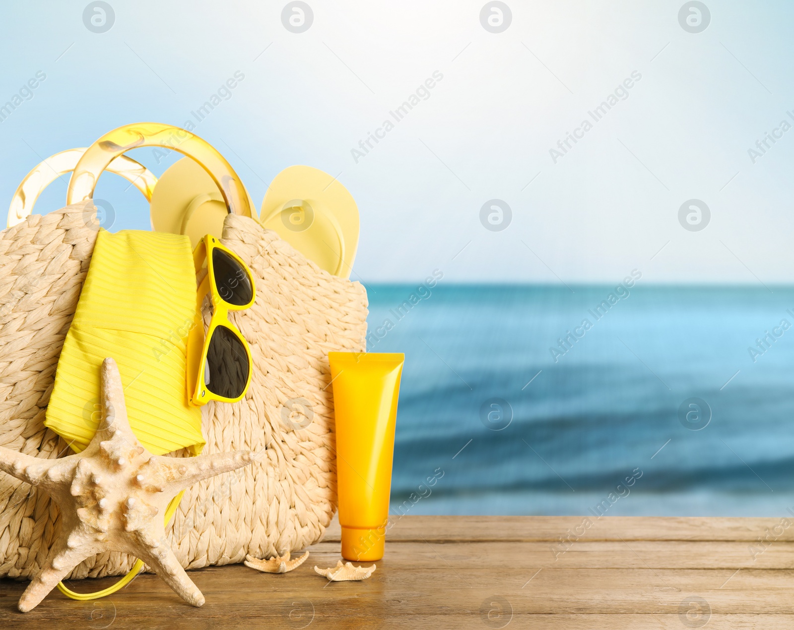 Image of Different beach objects on wooden surface near sea, space for text 